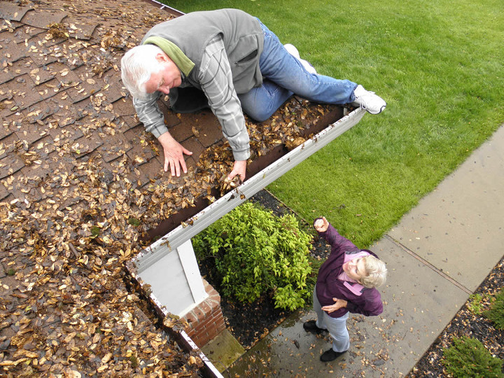 Man on roof cleaning gutters