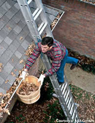 Man cleaning gutters balancing on a ladder