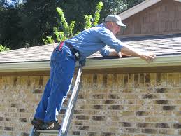 Man balancing on a ladder and stretching to clean gutters